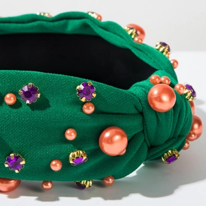 Détail d'un bandeau noué vert avec perles orange et ornements de strass violets