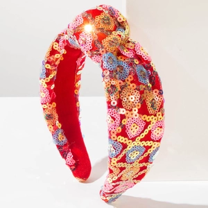 Macro shot of red knotted headband with colorful sequins forming pink hearts and dots