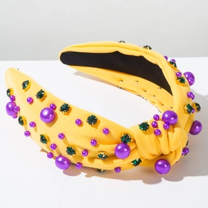 Détail d'un serre-tête noué jaune avec perles violettes et pierres précieuses vertes