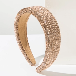 Detail of luxurious wide headband covered in sparkling champagne gold rhinestones