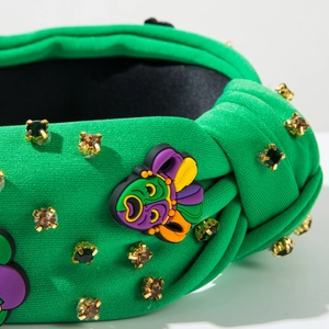 Détail du bandeau tricoté vert avec des strass et un patch de masque de carnaval