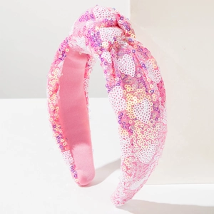 Close-up of pink sequined knot headband with white heart patterns and soft inner lining