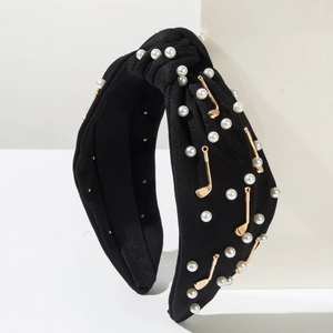 Détail d'un serre-tête noir noué avec perles fantaisie et breloques de golf dorées