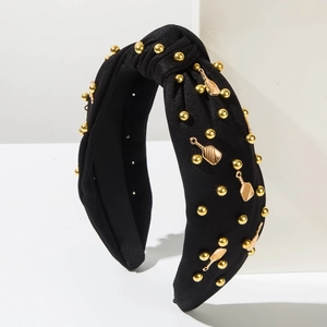 Détail d'un serre-tête noir noué avec breloques dorées et pendentifs en forme de cuillère