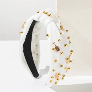 Détail d'un serre-tête noué blanc avec perles dorées et breloques en forme de raquette
