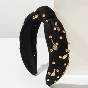 Détail d'un serre-tête noué noir avec des perles dorées et breloques raquettes de tennis