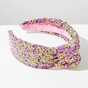 Detail van een brede geknoopte haarband met kleurrijke pailletten en roze binnenvoering