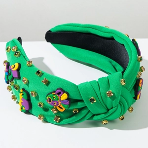 Détail du serre-tête noué vert avec strass dorés et breloques de masques de carnaval