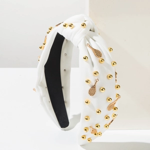 Détail d'un serre-tête noué blanc avec perles dorées et pendentifs raquettes de tennis