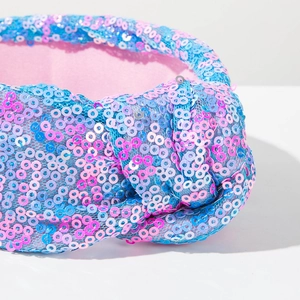 Detailopname van de knoop op de roze en blauwe hoofdband met glinsterende lovertjes