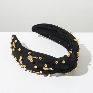 Détail du serre-tête noué noir avec breloques raquettes de tennis dorées et perles
