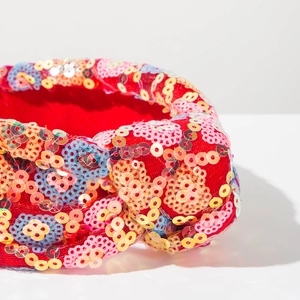 Detailed macro view of colorful sequins on a red knotted headband with floral patterns
