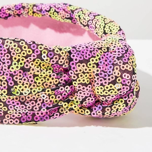 Detail van geknoopte haarband met kleurrijke pailletten en roze stoffen binnenvoering