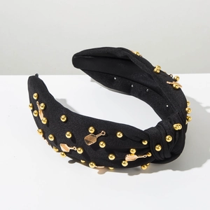 Détail d'un serre-tête noué noir avec rivets dorés et ornements en forme de raquette