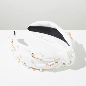 Détail d'un serre-tête blanc noué orné de perles et de pendentifs de golf dorés