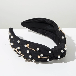 Détail du serre-tête noué noir avec perles blanches et accessoires de golf dorés