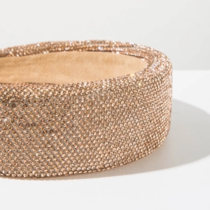 Close-up detail of champagne gold wide headband with shimmering crystal rhinestone embellishment