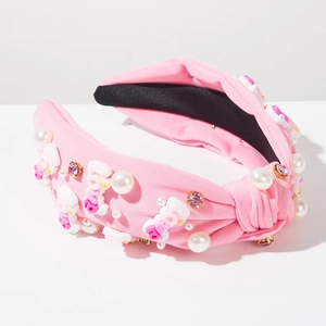 Detail eines rosa geknoteten Stirnbands mit Kunstperlen, Strasssteinen und LOVE-Schriftzug