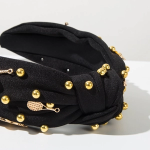 Détail du bandeau noir noué avec perles dorées et pendentifs de raquettes de tennis