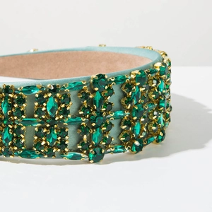 Detailed view of luxury mint green headband with dark green crystals and gold claws