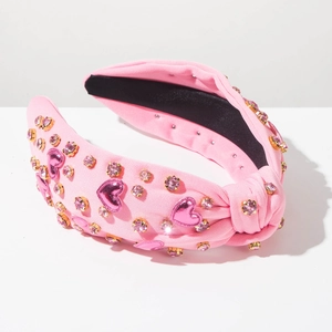Detailansicht eines rosa geknoteten Stirnbands mit Herz-Pailletten und Strasssteinen