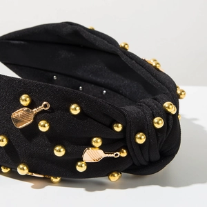 Gros plan sur un serre-tête noué noir avec perles dorées et pendentifs de raquette