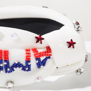 Détail d'un serre-tête blanc noué avec perles rouges, bleues, blanches et strass étoiles