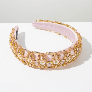 Macro detail of a thick pink satin headband with crystals and white floral appliques