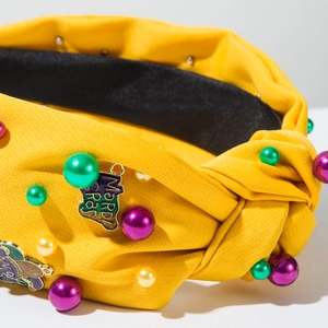 Close-up of Mardi Gras yellow knotted headband with colorful beads and gold pendant