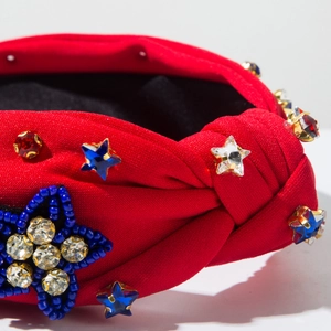 Macro detail of red fabric headband with beaded star patch and colorful crystals