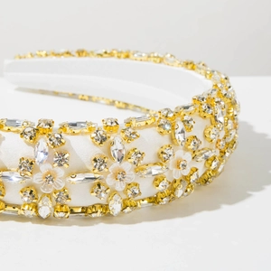 Detail of luxury white sponge headband with gold metal claw-set crystals and floral accents