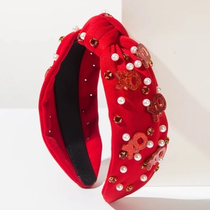 Détail d'un serre-tête noué rouge avec accents de perles et lettres scintillantes XOXO