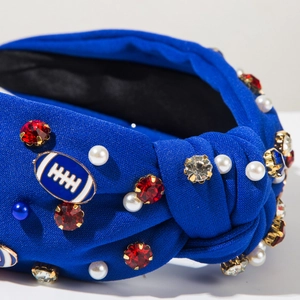 Detail of blue knotted headband with rugby charm, red rhinestones and white pearls