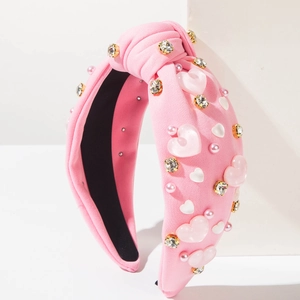 Détail du serre-tête rose noué orné de cœurs en résine, perles et cristaux brillants