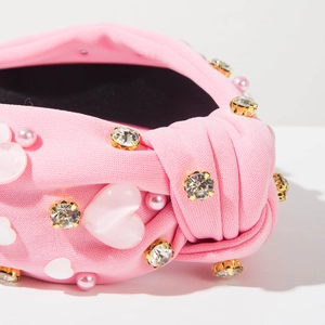 Détail d'un serre-tête rose avec strass, perles et cœurs en résine sophistiqués