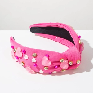 Détail du serre-tête rose noué avec pierres en cœur, perles et strass brillants