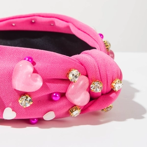 Détail du serre-tête rose torsadé orné de perles en forme de cœur et de cristaux brillants