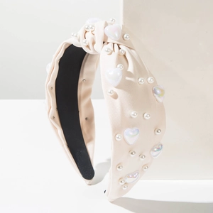 Gros plan détaillé du serre-tête beige avec perles, perles de cœur et nœud élégant
