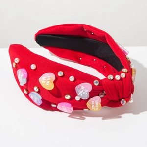 Detail of red knotted headband with pearls, crystals and romantic heart charms