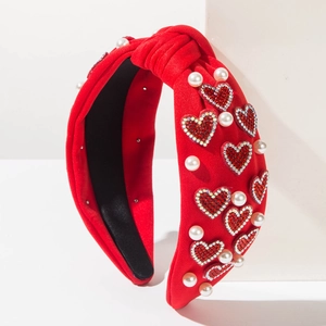 Red knotted headband with sparkling rhinestones, heart charm and pearl accents on white
