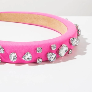 Detailed close-up of bright pink satin headband with hand-sewn crystal heart embellishments