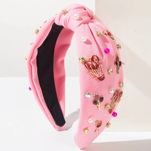Détail d'un serre-tête en tissu rose avec perles, strass et breloques cœur LOVE