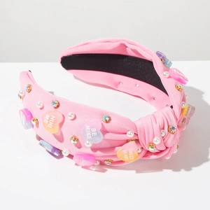 Detail of pink knotted headband with pearls, rhinestones and 'HUG ME' heart charms