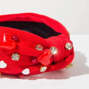 Détail d'un serre-tête en tricot rouge avec strass, perles et ornements en cœur