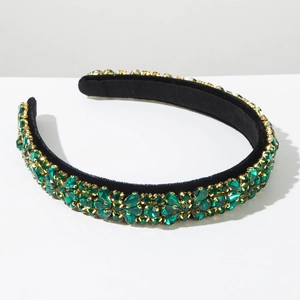 Macro detail of emerald green rhinestones on black velvet headband with golden metal claws
