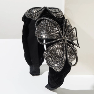 Luxurious black velvet headband with sparkling rhinestone flower on white stage