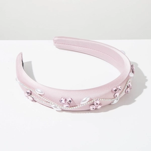 Détail du serre-tête rembourré rose avec fleurs en strass, perles et fini satiné