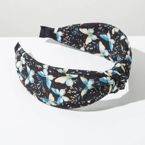 Détail du serre-tête large noué avec motifs de papillons bleus et fleurs sur tissu noir