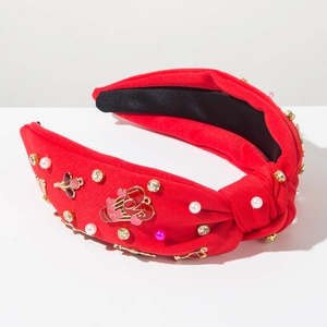 Détail d'un serre-tête rouge orné de perles, strass et breloque cœur love