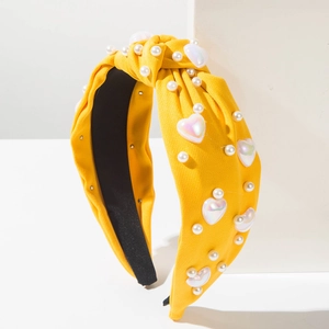 Détail d'un serre-tête en tissu jaune avec perles et breloques en forme de cœur